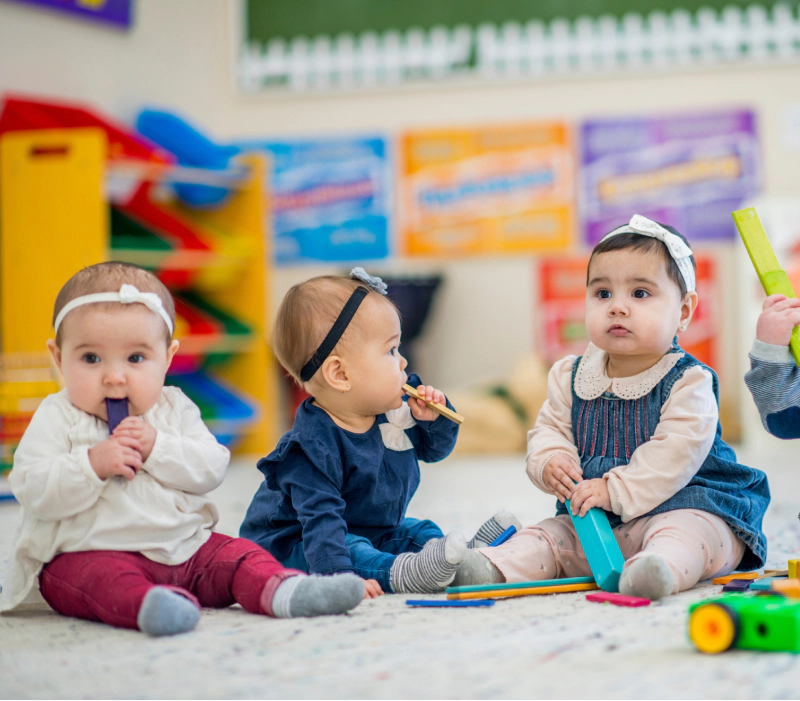 babies sitting on daycare floor playing with toys